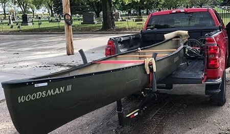 A red short bed truck carrying a kayak with a hitch extension